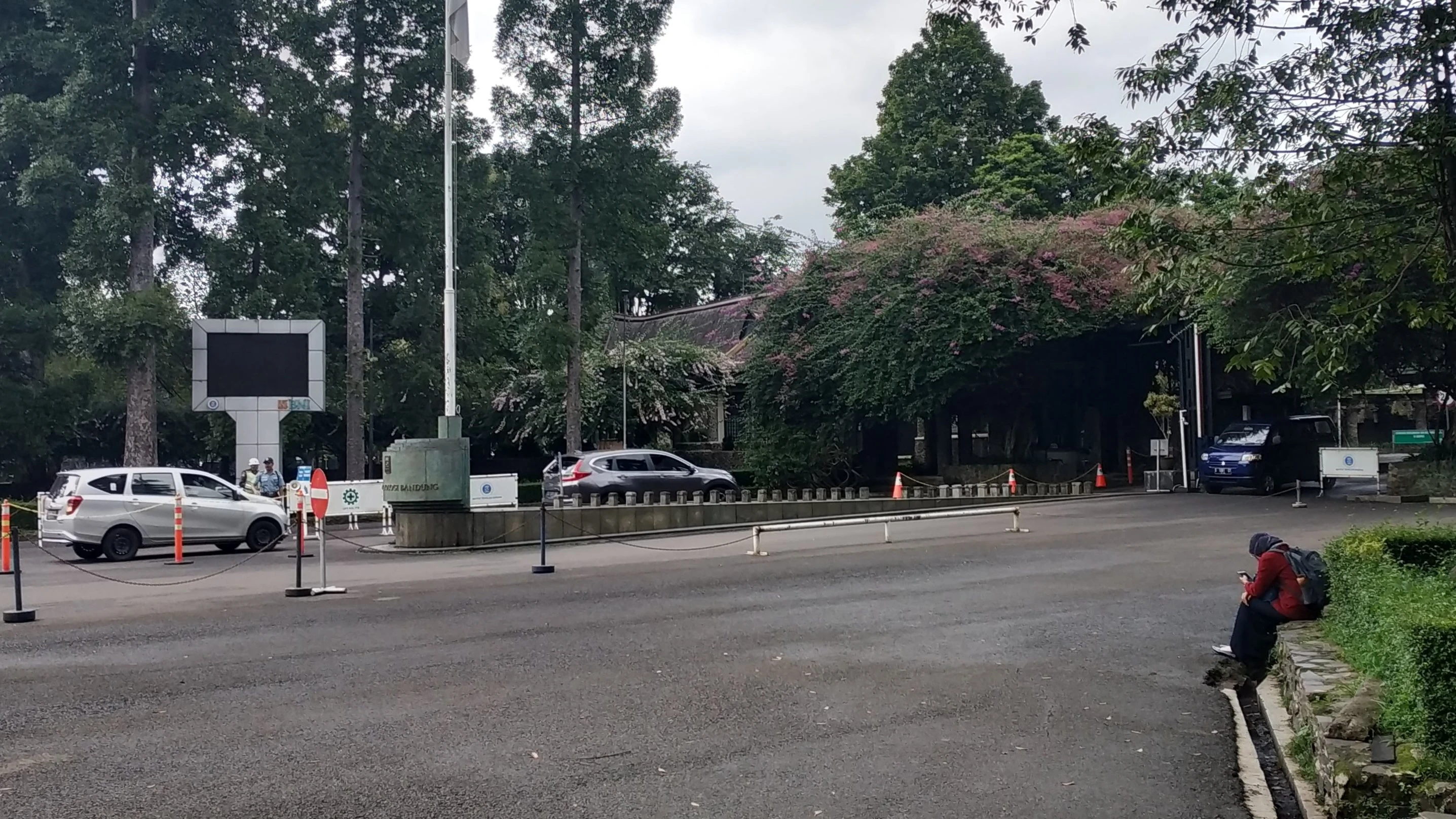 a view of the ITB campus gate and a woman seemingly staring into the distance